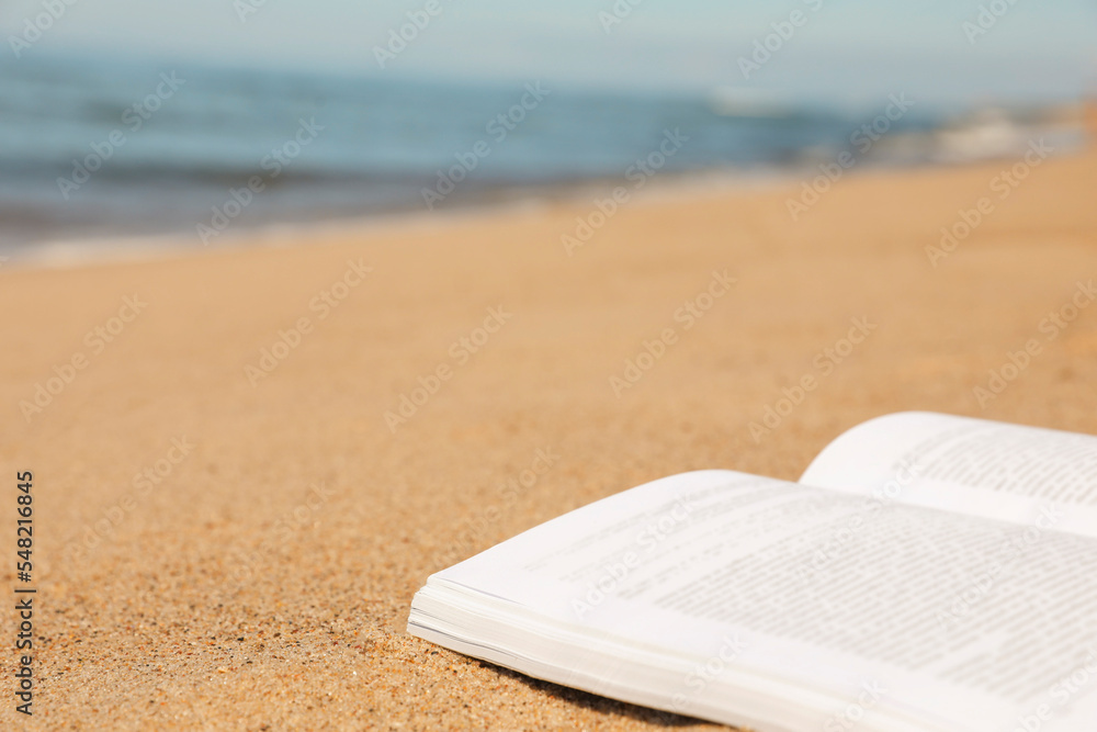 Open book on sandy beach near sea, closeup. Space for text Open book on sandy beach near sea, closeup. Space for text