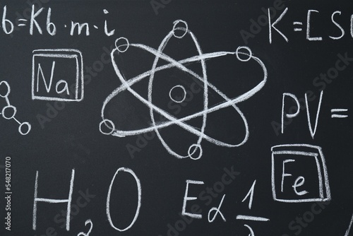 Different chemical formulas written with chalk on blackboard, closeup