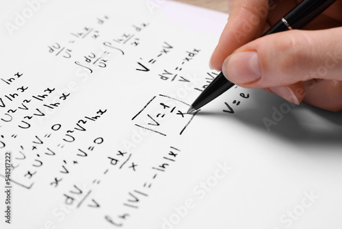 Obraz na plátně Student writing different mathematical formulas on paper, closeup