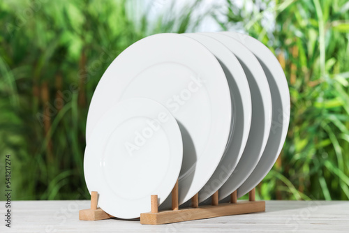 Many clean plates on white table against blurred background