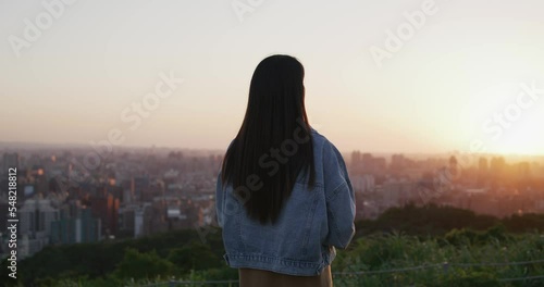 Back rear view of woman look at the city under sunset