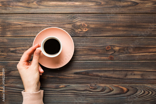 Minimalistic style woman hand holding a cup of coffee on Colored background. Flat lay, top view espresso cup. Empty place for text, copy space. Coffee addiction. Top view, flat lay
