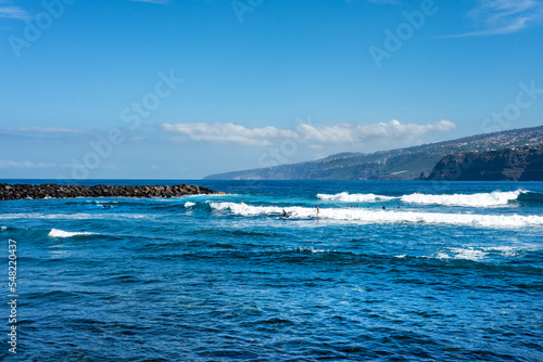 Young people surfing on the coast of Puerto de la Cruz, in Tenerife. Canary Islands. Spain.