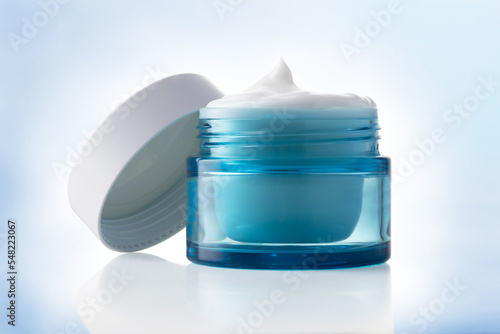 white beauty cosmetic cream in blue glass jar on light blue.