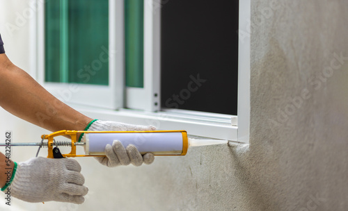 Construction worker using silicone sealant caulk the outside window frame. photo