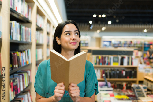 Happy woman enjoying an interesting novel at the book shop