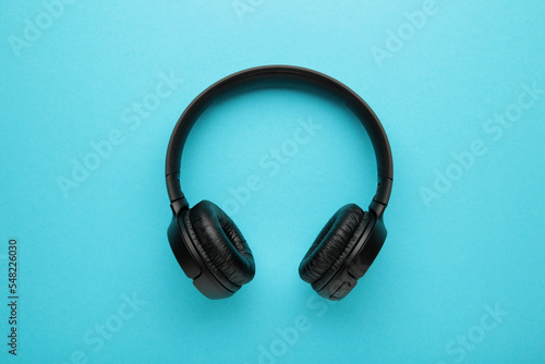 Black, modern wireless headphones on a blue background.