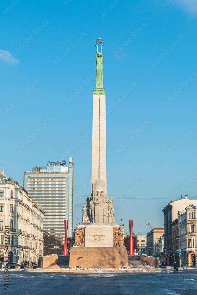 The Freedom Monument in winter, monument honouring soldiers killed during the Latvian War of Independence, symbol of the freedom, independence and sovereignty with flags of Latvia in Riga