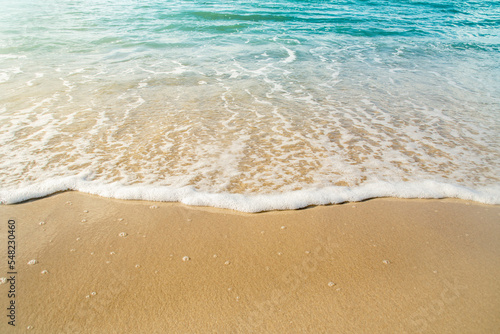 Close-up of a beach with a calm transparent wave. Romantic sea coast with golden sand.