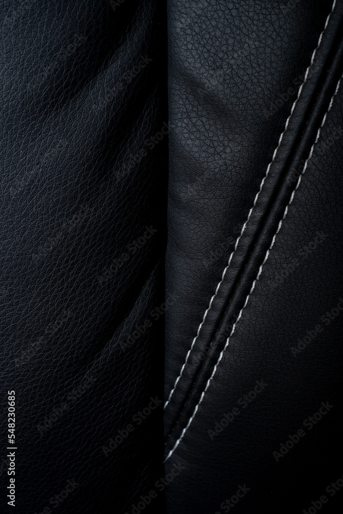 Close-up of the surface of black leather furniture stitched with white threads. Close-up of the surface of black leather furniture stitched with white threads.