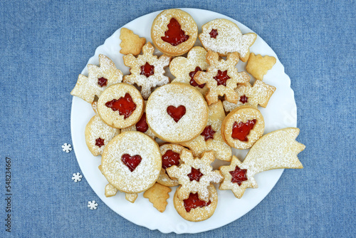Various shapes of Linzer cookies filled with strawberry jam on a plate