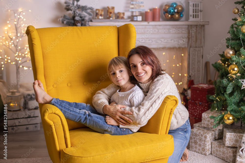 Cute child, boy, sitting in yellow armchair in a decorated room for Christmas Cute child, boy, sitting in yellow armchair in a decorated room for Christmas