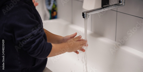 manine di bimbo che vengono lavate con acqua del rubinetto e sapone photo