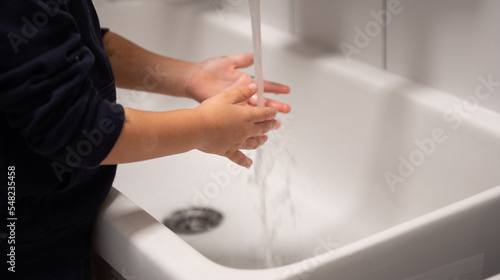 manine di bimbo che vengono lavate con acqua del rubinetto e sapone photo