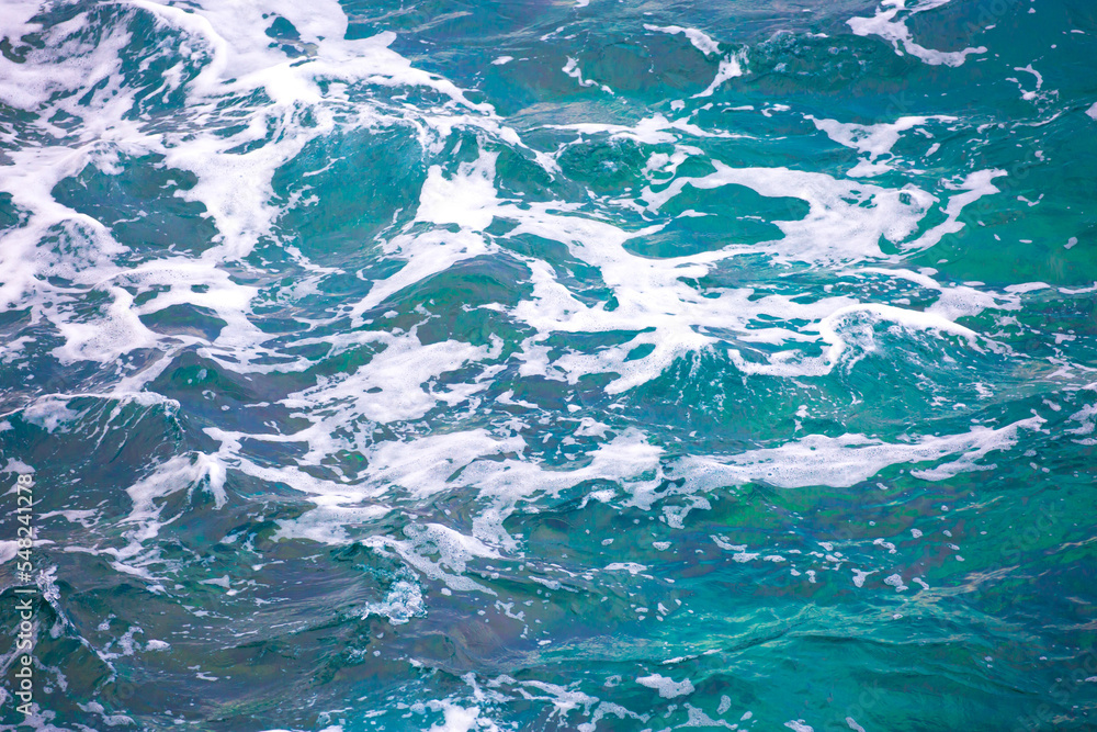 Fototapeta premium Water background, turquoise shallow sea water. Beautiful texture of sun glare on the water. sea foam