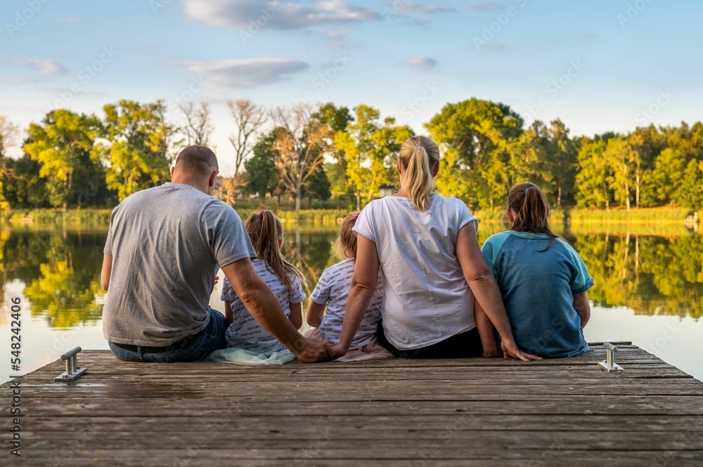 Φωτογραφία Lovely family with three kids sitting on a wooden dock over a lake on a sunny da