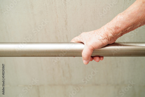 Asian elderly old woman patient use toilet support rail in bathroom, handrail safety grab bar, security in nursing hospital.