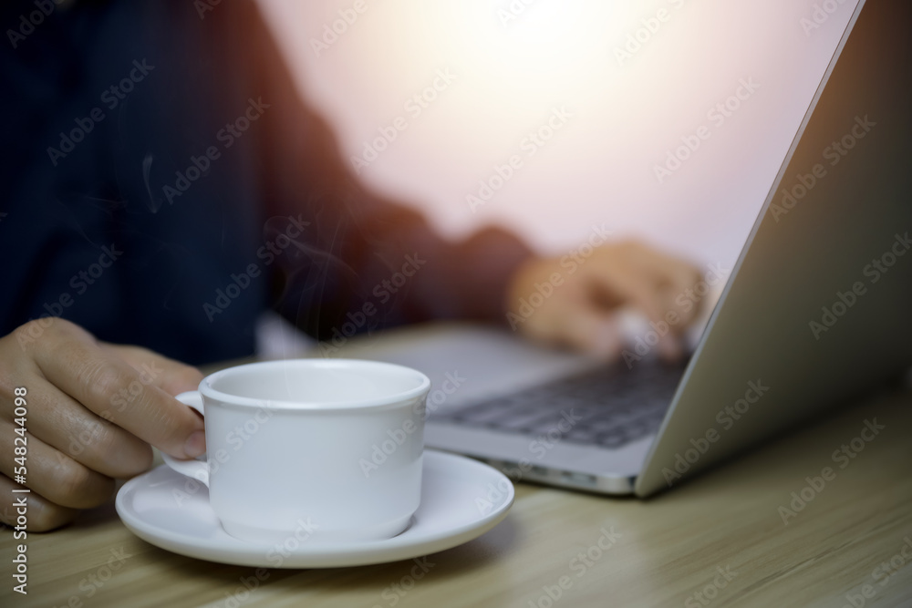 Businessman working in front of a laptop With a cup of hot coffee that has smoke and steam


