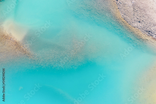 Clear azure water in a mountain lake. The shore with stones. View of the water from a drone. Landscape from the air. Natural landscape as wallpaper. Mountain lakes of Alberta, Canada.
