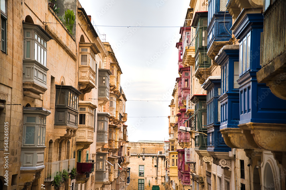 Facades of historical houses in the old town .Typical narrow street with colorful balconies in Valletta , Malta