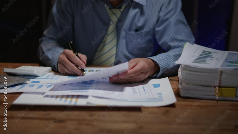 Close up of business hands working overtime night shift and calculating on financial and accounting graft and chart in office space Close up of business hands working overtime night shift and calculating on financial and accounting graft and chart in office space