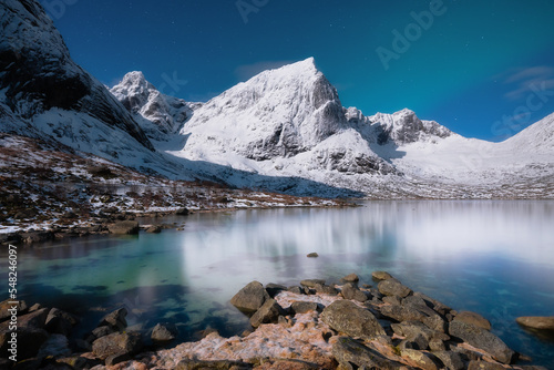 Norway, Lofoten island. Mountains and reflections on water at night. Winter landscape. The sky with stars and Aurora borealis. Nature as a background. North travel.