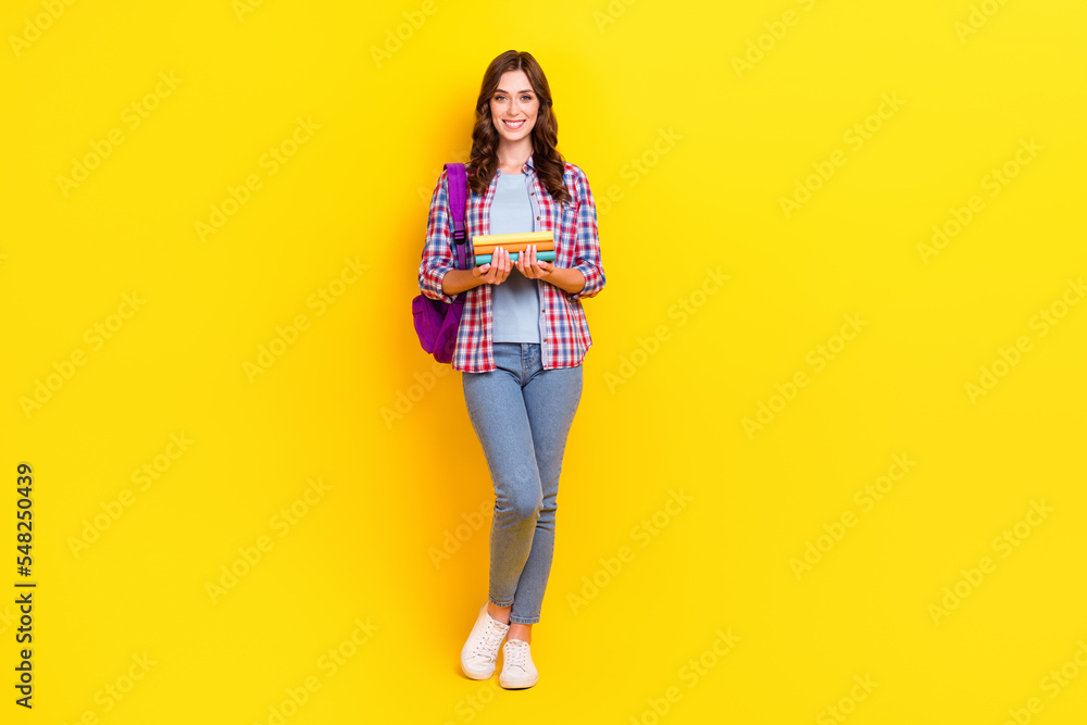 Full body size photo of young satisfied woman hold stack books backpack preparation next exam science isolated on yellow color background Full body size photo of young satisfied woman hold stack books backpack preparation next exam science isolated on yellow color background