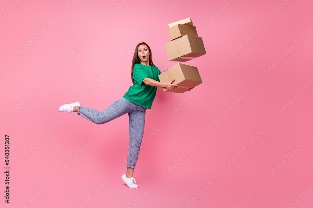 Full size photo of impressed gorgeous clumsy girl dressed green t-shirt jeans falling with boxes isolated on pink color background Full size photo of impressed gorgeous clumsy girl dressed green t-shirt jeans falling with boxes isolated on pink color background