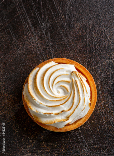 Lemon curd and meringue tartlet, top view, over rustic background
