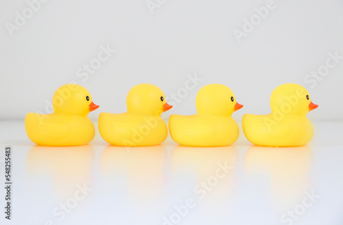 Quadro em tela Four yellow rubber ducks in a row lined up in single file facing rightward direction, with reflection, idiom and phrase concept for organisation, to get one’s ducks in a row