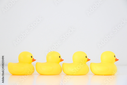 A row of four yellow rubber ducks lined up in single file facing rightward direction, idiomatic and phrase concept for organisation, to get one’s ducks in a row, business and work speak