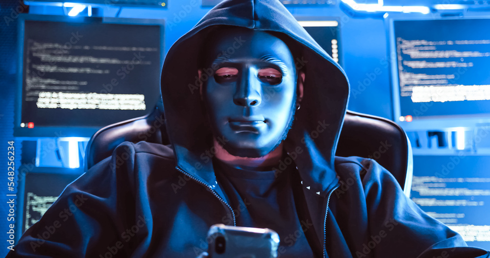 A hacker wearing a mask to cover his face is using computer to hack data to get ransom from victims. A hacker wearing a mask to cover his face is using computer to hack data to get ransom from victims.