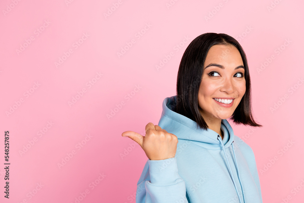 Photo of cute dreamy girl dressed blue sweatshirt looking pointing thumb back empty space isolated pink color background Photo of cute dreamy girl dressed blue sweatshirt looking pointing thumb back empty space isolated pink color background