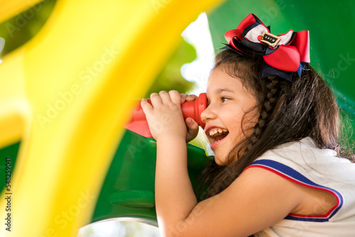 criança sorridente olhando através de telescópio de brinquedo photo