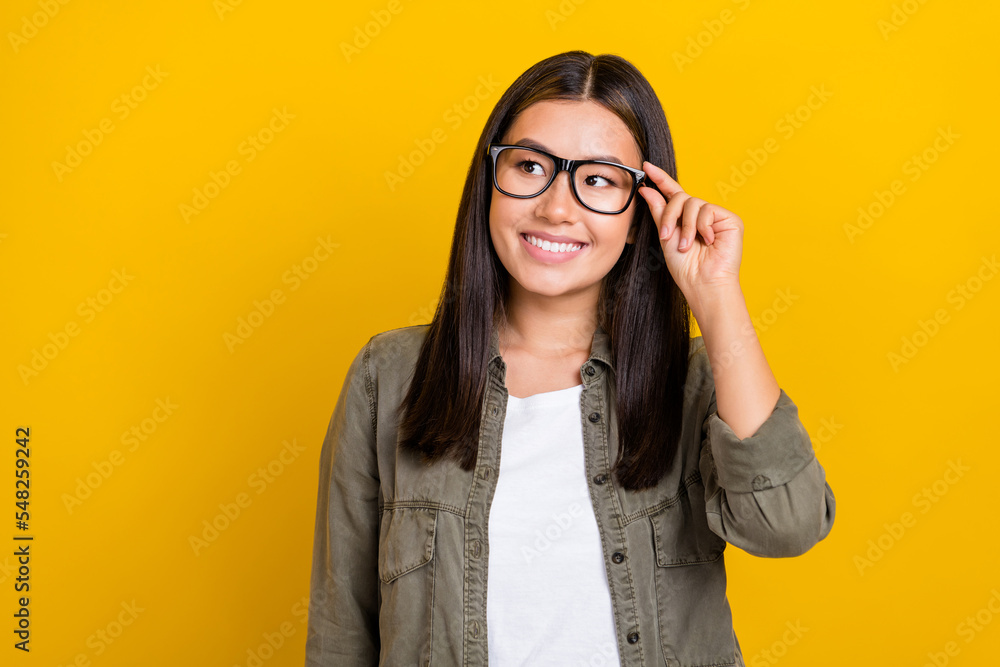Portrait of gorgeous clever woman with long hairdo wear khaki shirt look empty space touch glasses isolated on yellow color background Portrait of gorgeous clever woman with long hairdo wear khaki shirt look empty space touch glasses isolated on yellow color background