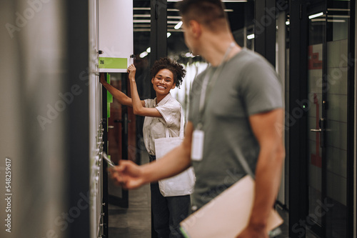 Joyful office worker and her coworker opening section lockers
