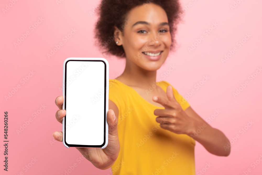 Smiling millennial african american curly woman point finger at phone with empty screen