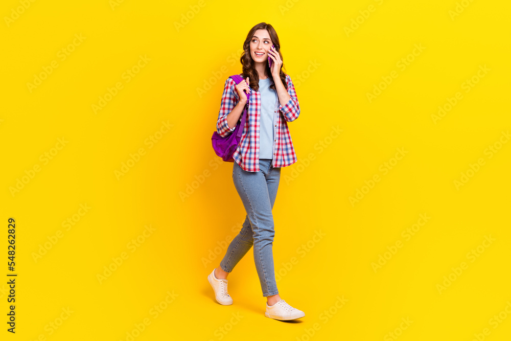 Full body length photo of attractive cute student lady walking talking smartphone look mockup good news isolated on yellow color background Full body length photo of attractive cute student lady walking talking smartphone look mockup good news isolated on yellow color background