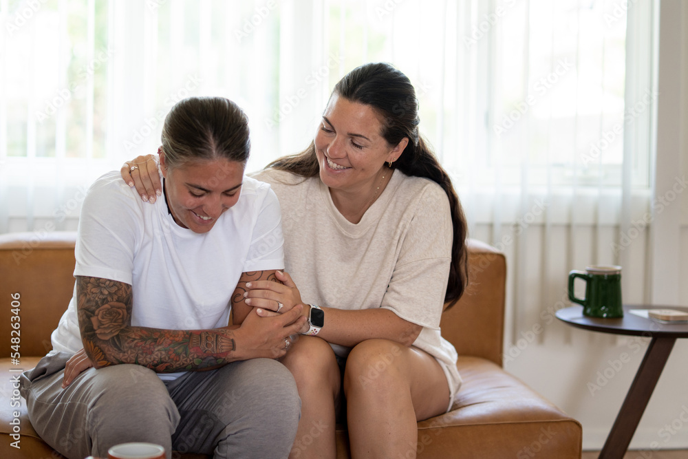 Adult lesbian couple comforting each other on couch at home Adult lesbian couple comforting each other on couch at home