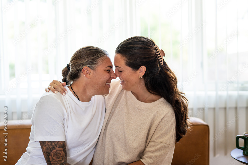Adult lesbian couple intimate on couch at home Adult lesbian couple intimate on couch at home