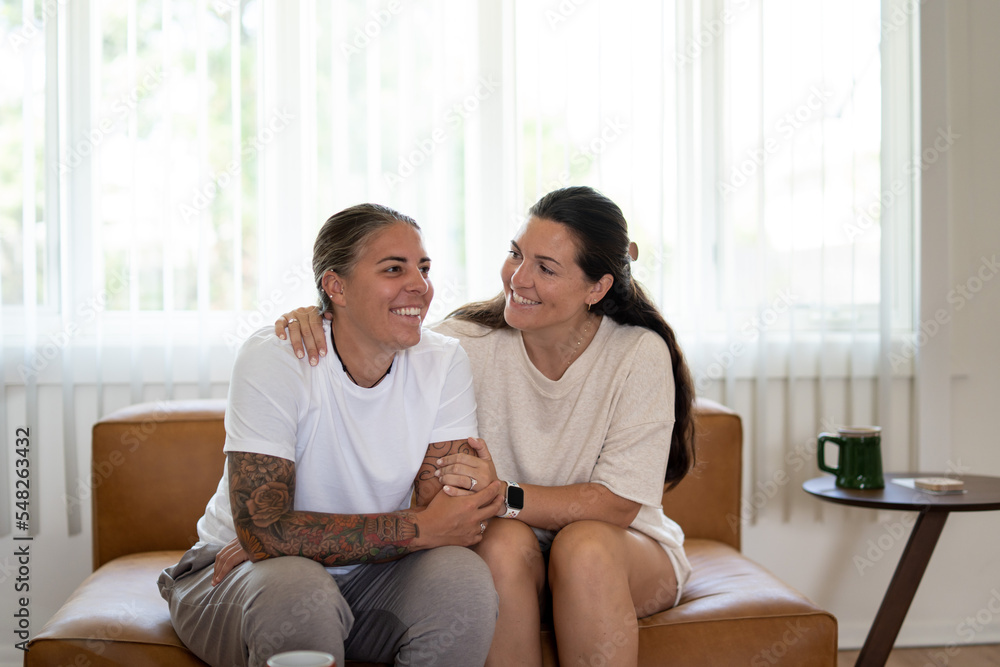 Adult lesbian couple comforting each other on couch at home Adult lesbian couple comforting each other on couch at home