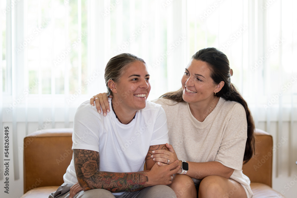 Adult lesbian couple comforting each other on couch at home Adult lesbian couple comforting each other on couch at home