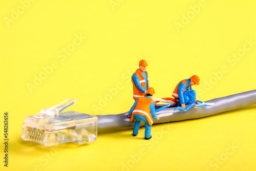 Conceptual image of miniature figure workmen investigating a fault on a broadband network cable