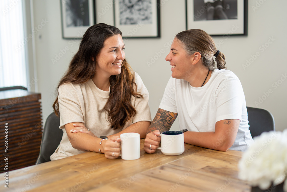 Adult lesbian couple have coffee together in dining room Adult lesbian couple have coffee together in dining room