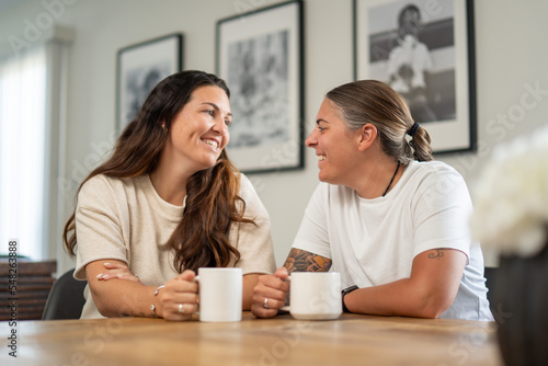 Adult lesbian couple have coffee together in dining room