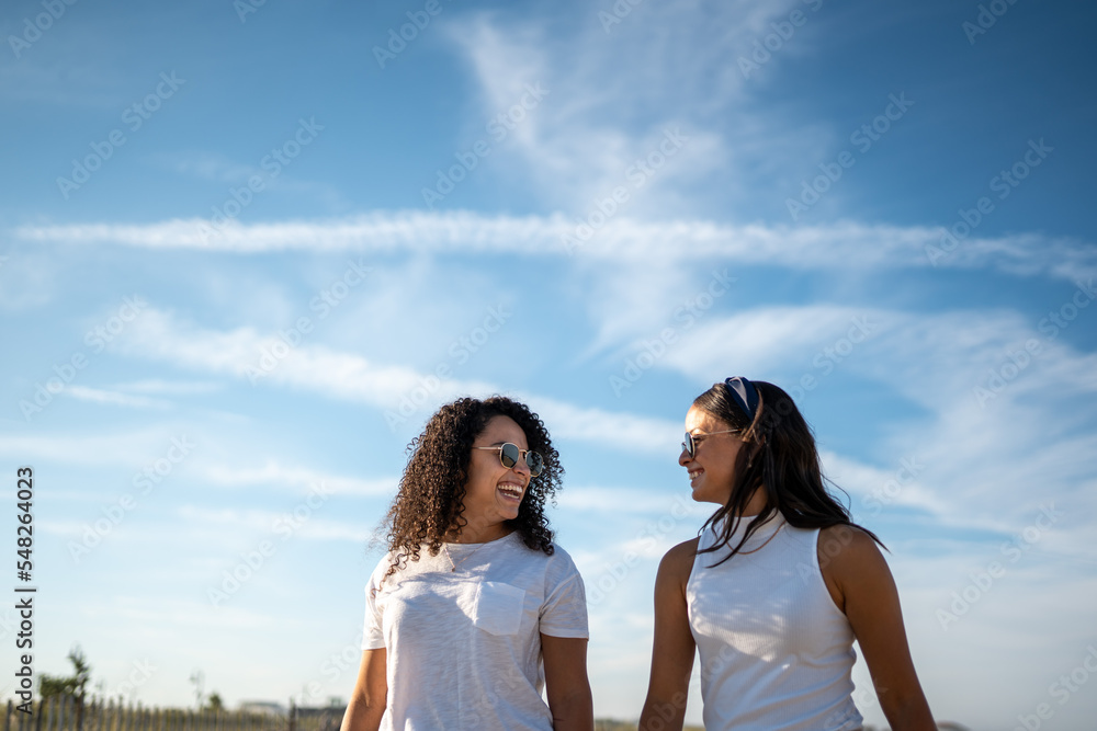 Hispanic lesbian couple laugh under blue sky Hispanic lesbian couple laugh under blue sky