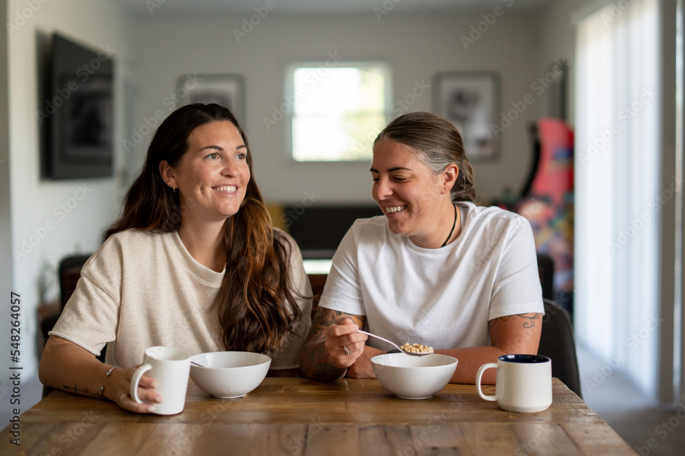 Adult lesbian couple have breakfast together in dining room Adult lesbian couple have breakfast together in dining room