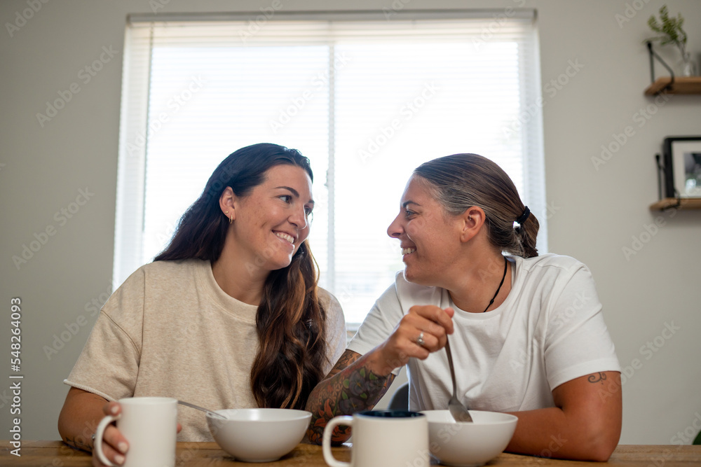 Adult lesbian couple have breakfast together in dining room Adult lesbian couple have breakfast together in dining room