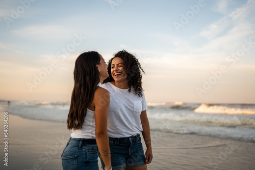 Hispanic lesbian couple stand by the ocean holding hands © Brett Edwards/Adobe Stock