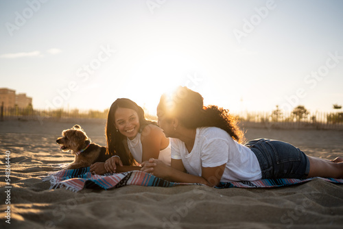 Hispanic lesbian couple lie on blanket at the beach photo